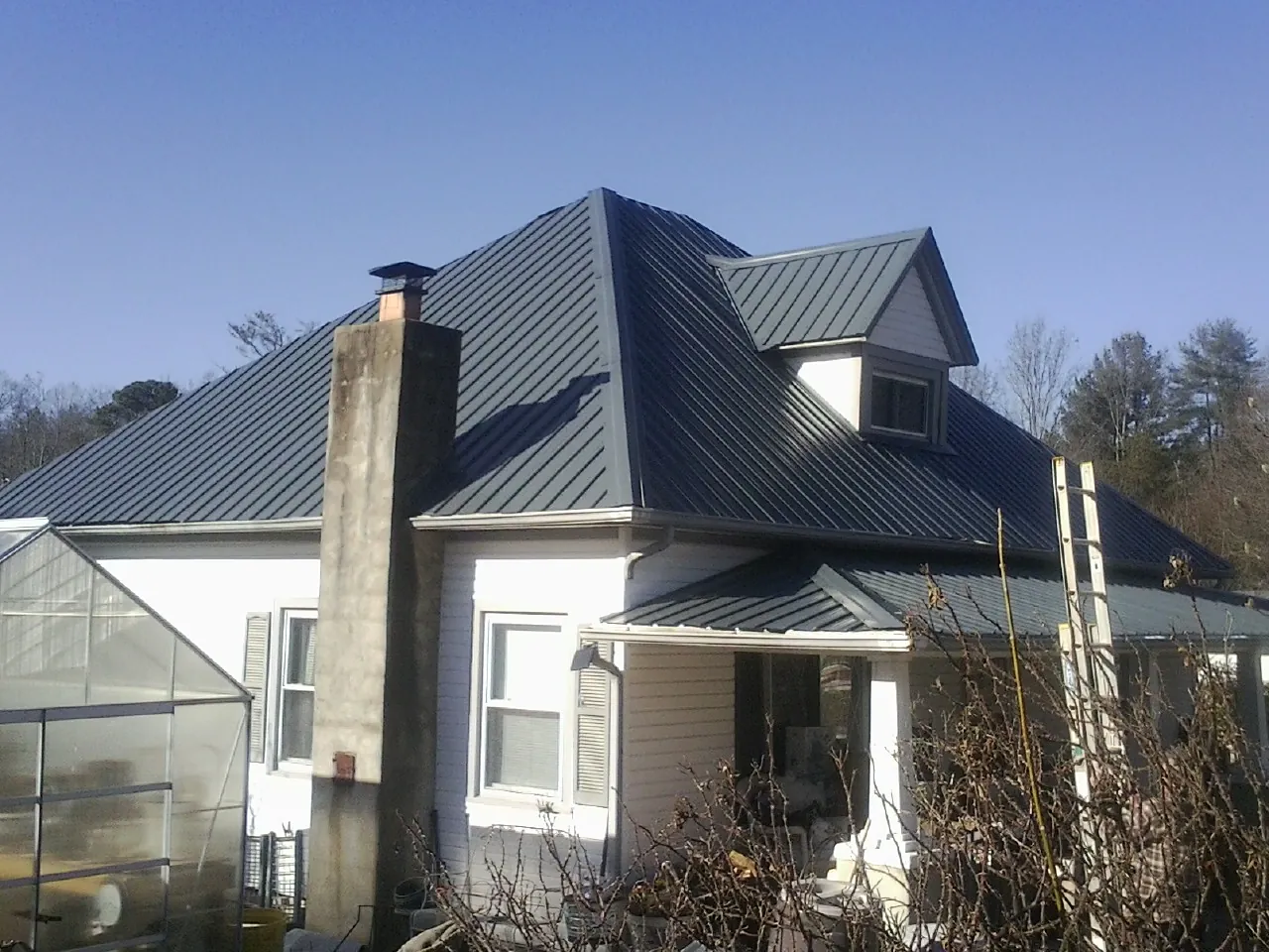 Dark blue standing seam metal roof on a white farmhouse with dormer — Slate & Tile Roof Repair by Roofing Brothers in Whitesburg