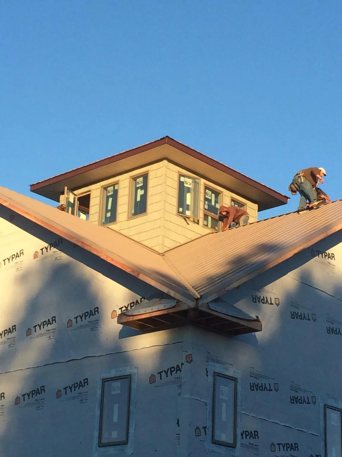 Roofers working around a rooftop cupola on a new metal roof at sunset — Roof Waterproofing in Whitesburg by Roofing Brothers
